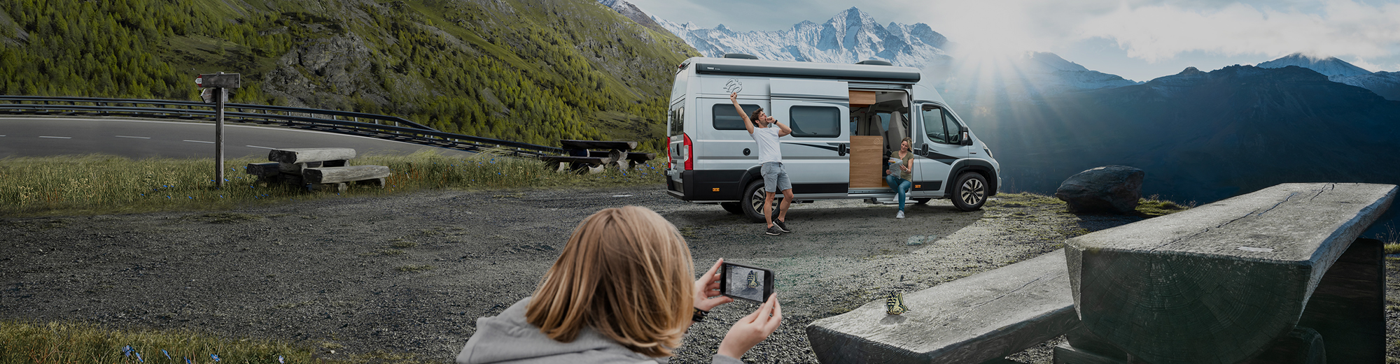 Eine Familie steht mit einem Wohnmobil auf einem Rastplatz.