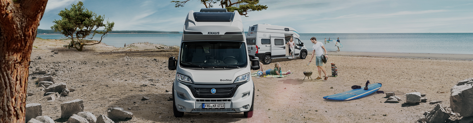 Zwei Familien parken mit ihren Wohnmobilen am Strand, um zu grillen.